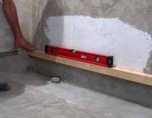 Placer et fixer la barre sur le mur pour la pose de la première rangée de carreaux